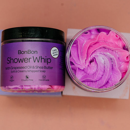 Purple container of BonBon Shower Whip whipped soap with pink whipped soap on a beige background by Stellia Beauty