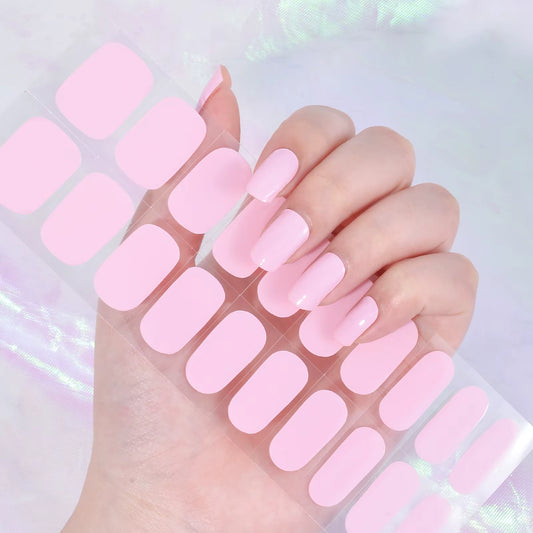 Hand with pink gel nail wraps and a clear container of matching pink gel nail wraps on a light background by Stellia Beauty