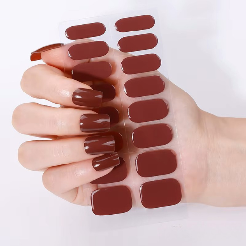 Hand holding a set of brown nail wraps against a white background by Stellia Beauty