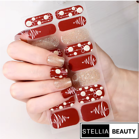 Christmas Nail art stickers with red and gold designs held by a hand, branded with Stellia Beauty.