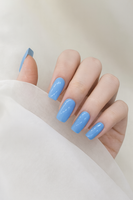 Hand with glossy blue gel nail wraps on a neutral background by Stellia Beauty