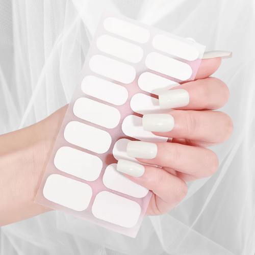 Hand holding a set of glossy white nail wraps - minimalist manicure style