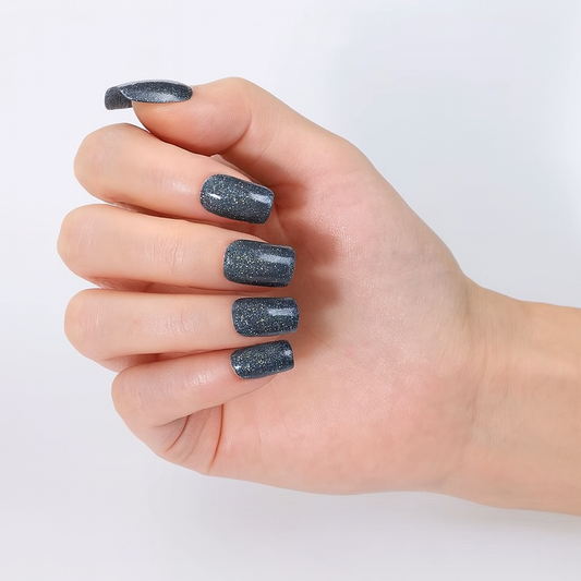 Hand with grey silver glittery nail wraps on a light background by Stellia Beauty
