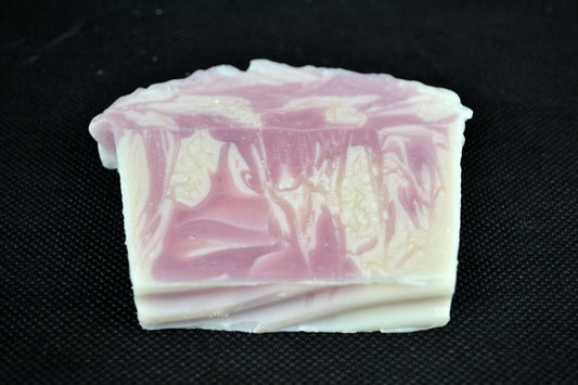 Block of pink and white marbled soap on a black background