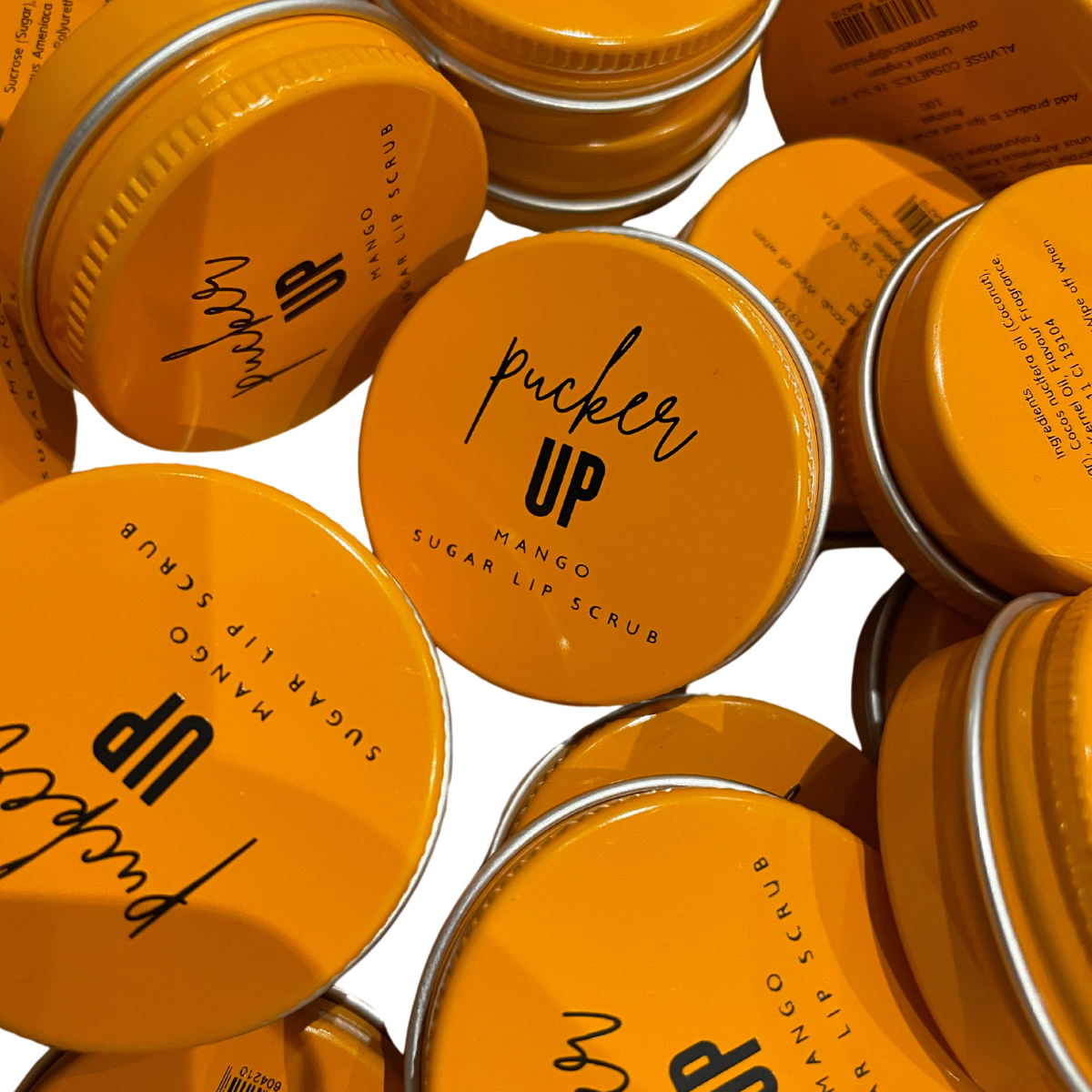 Multiple jars of 'Pucker Up' mango sugar lip scrub with orange lids by Stellia Beauty