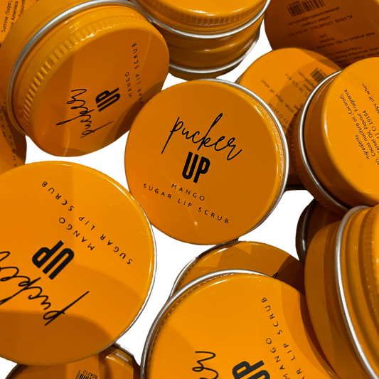 Multiple jars of 'Pucker Up' mango sugar lip scrub with orange lids by Stellia Beauty