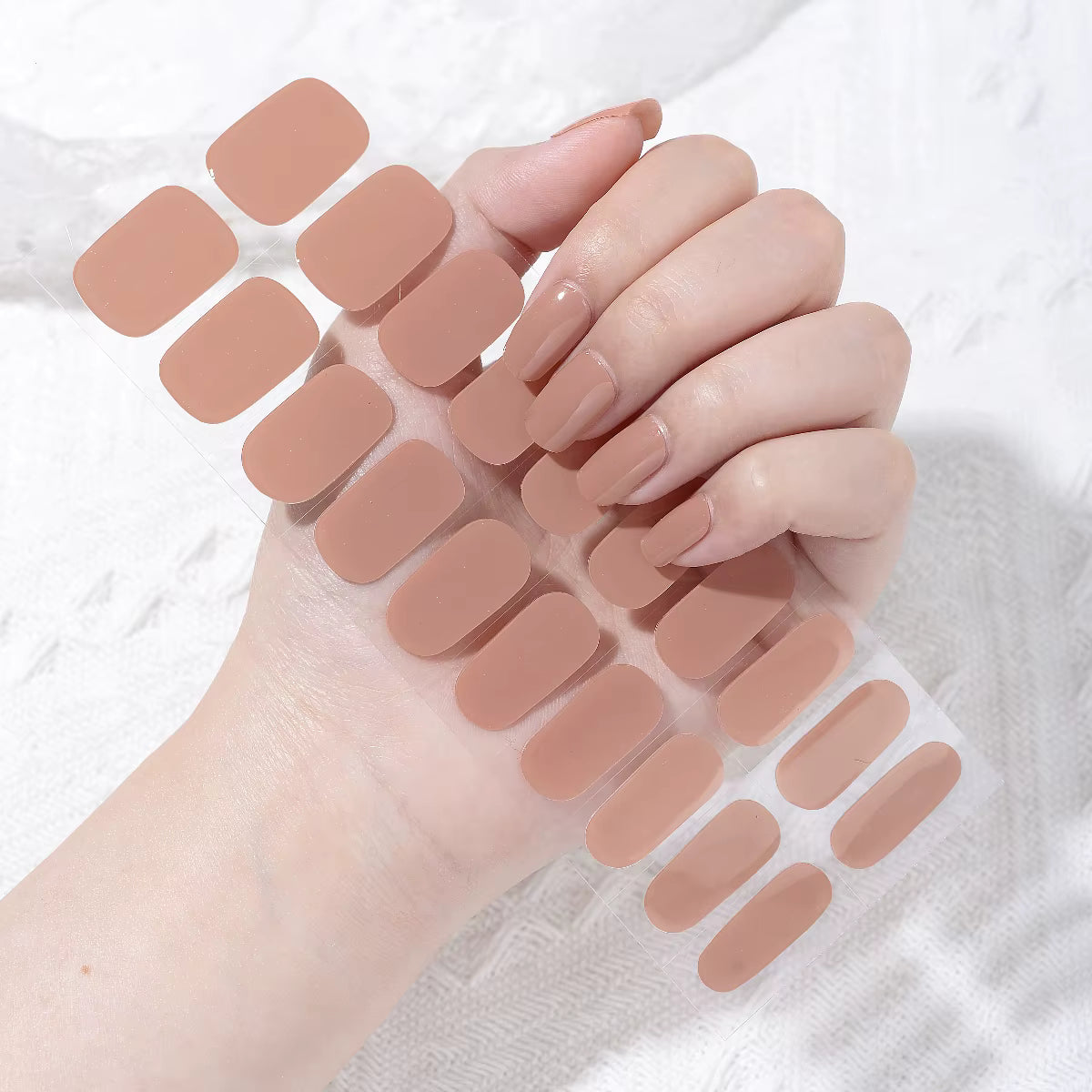 Hand with nude-colored nail wraps on a white background by Stellia Beauty