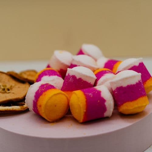 Pink Fizz & Pomello Mini Bath Bombs Colourful bath bombs on a white plate with a yellow background by Stellia Beauty