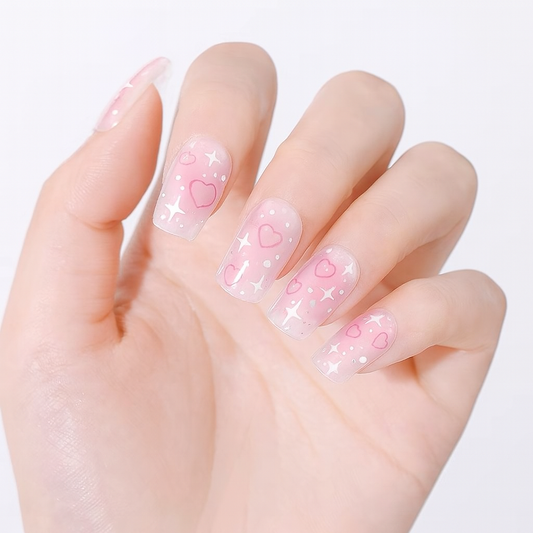 Hand with pink gel nail wraps featuring heart designs on a white background by Stellia Beauty