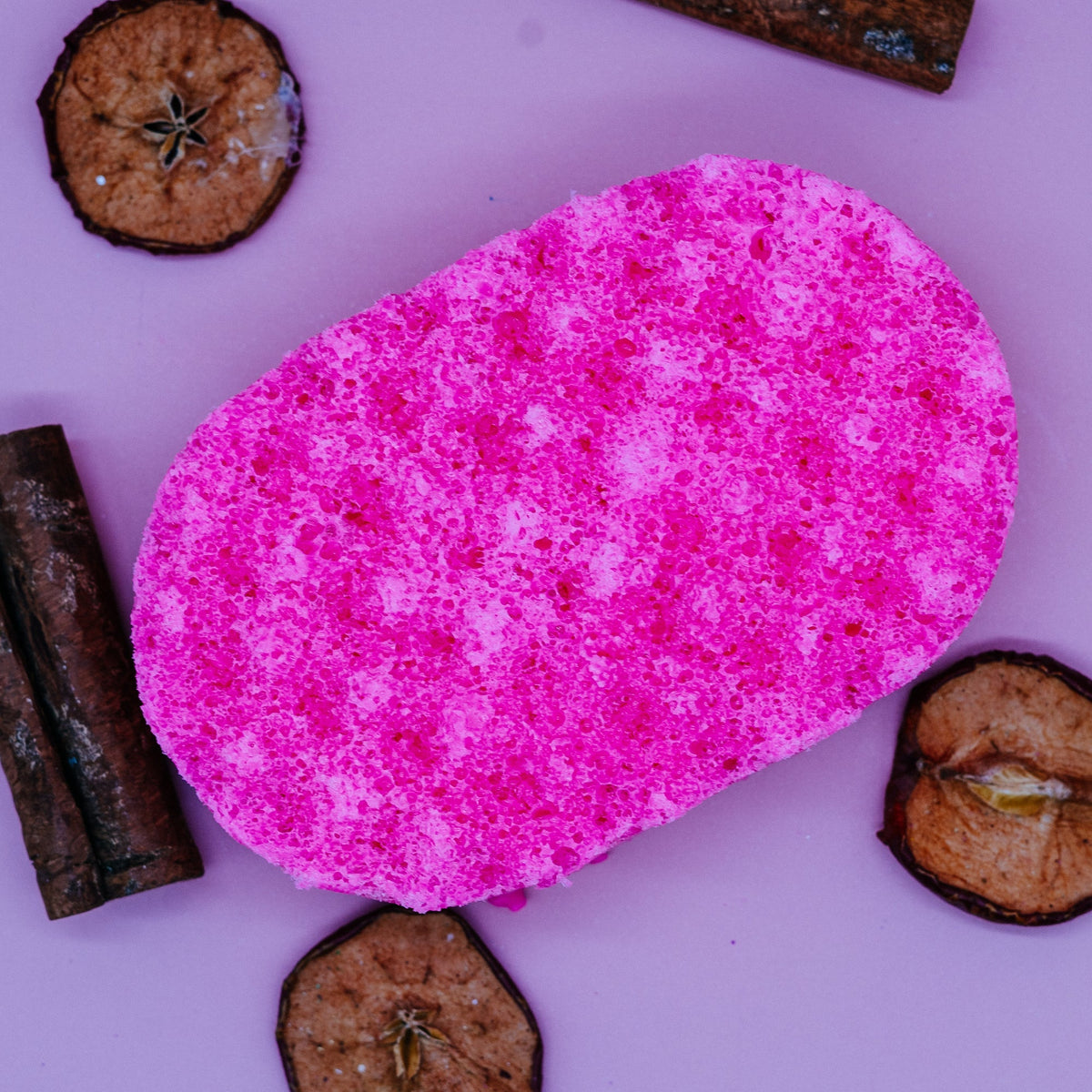 Pink exfoliating sponge soap on a pink background with dried fruits by Stellia Beauty