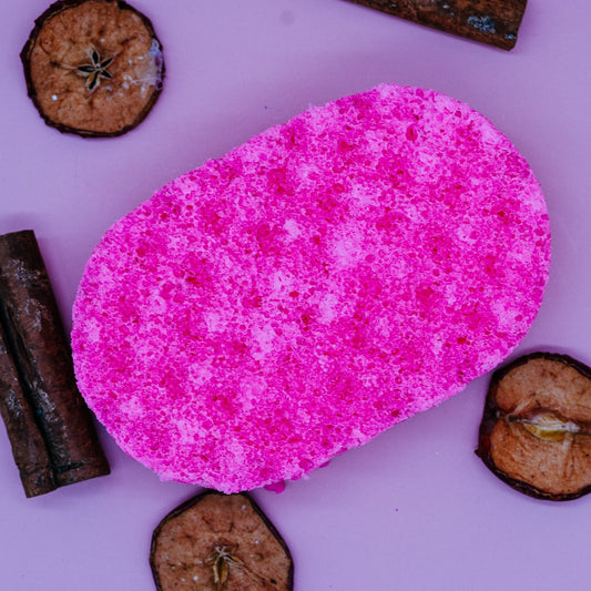 Pink exfoliating sponge soap on a pink background with dried fruits by Stellia Beauty