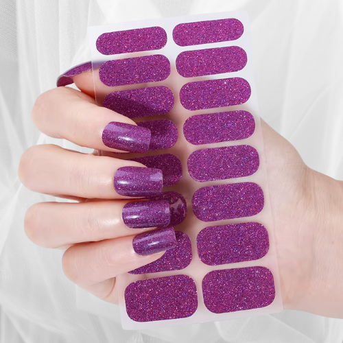 Hand with sparkling purple glitter nail wraps in various sizes – bold, glamorous manicure
