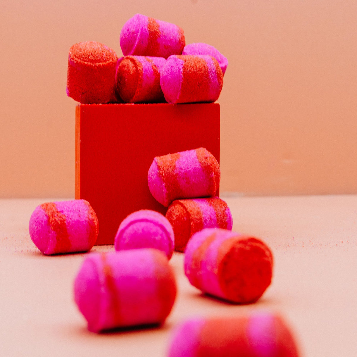 Strawberry & Cream Mini Bath Bombs Pink and red striped bath bombs in a red box on a beige background by Stellia Beauty