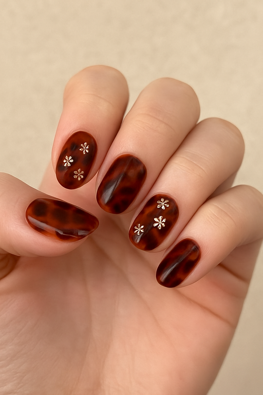 Hand with tortoiseshell nail design featuring white floral patterns on a beige background by Stellia Beauty