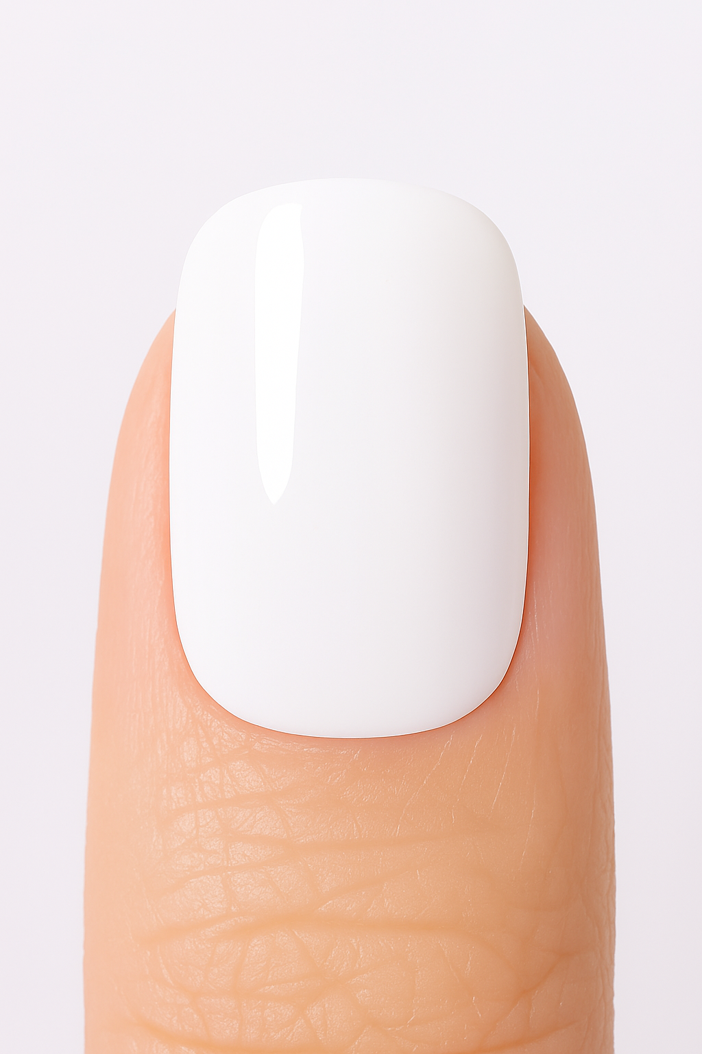 Close-up of a finger with a white gel nail wrap on a light grey background by Stellia Beauty