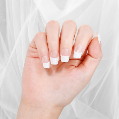 Hand wearing white tip fully cured gel nail wraps on a light background by Stellia Beauty