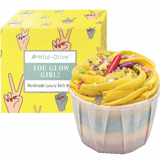 Yellow bath bomb with colourful sprinkles in a cupcake-shaped container, next to a yellow box with 'Wild Olive' branding. Sold by Stellia Beauty